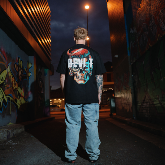 Person wearing a black t-shirt with a colorful skull design in an urban setting at night.